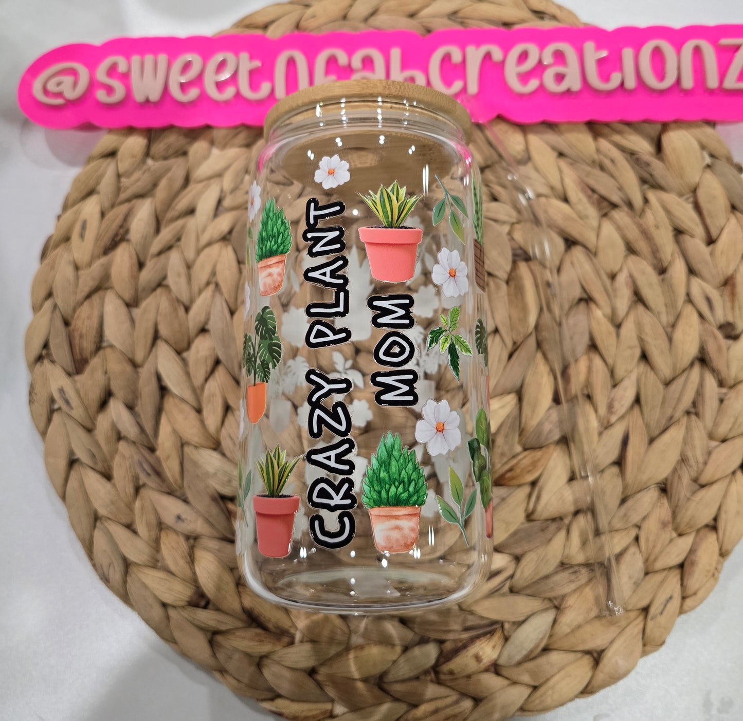 Clear tumbler with plant-themed design and text on a woven surface