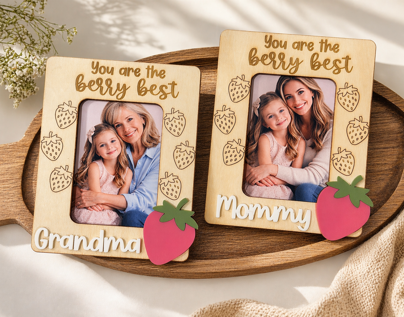 Two wooden picture frames with strawberry designs and family photos on a wooden tray.